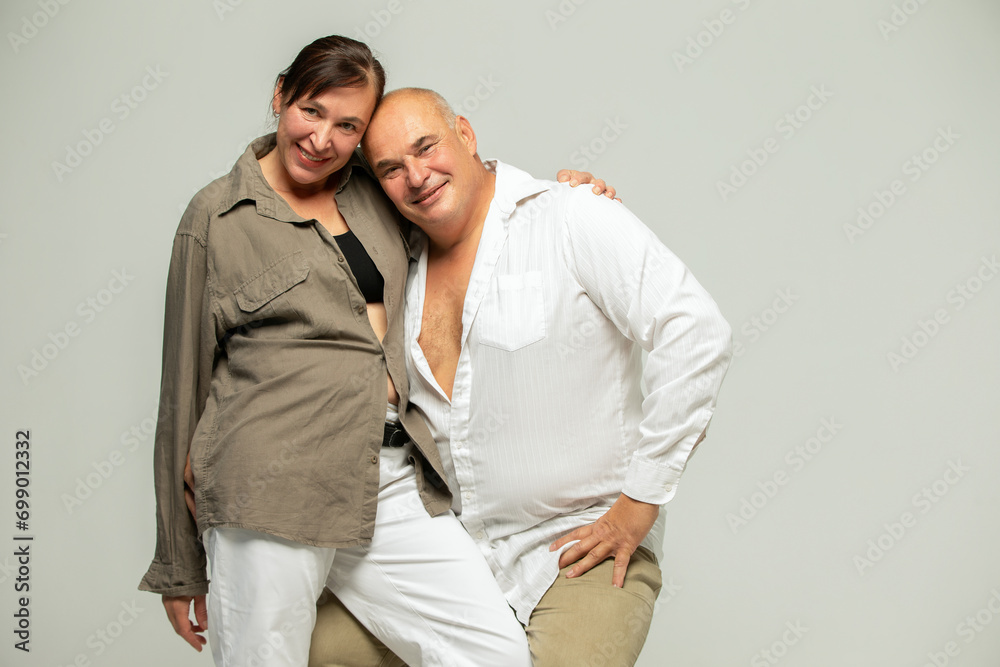 Portrait of a mature couple. Cheerful laughing funny couple two friends elderly gray-haired brunette man in casual clothes standing, hugging and looking at camera Portrait of a mature couple. Cheerful laughing funny couple two friends elderly gray-haired brunette man in casual clothes standing, hugging and looking at camera