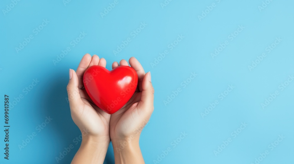 Hand holding a red heart on blue background, symbolizing appreciation for healthcare heroes on International Nurses Day. Hand holding a red heart on blue background, symbolizing appreciation for healthcare heroes on International Nurses Day.
