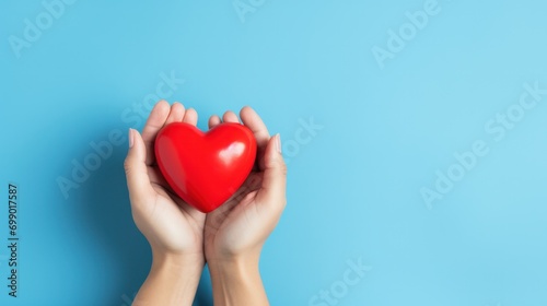 Hand holding a red heart on blue background  symbolizing appreciation for healthcare heroes on International Nurses Day.