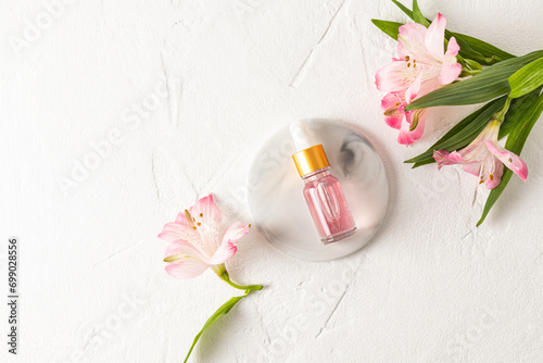 Fashion beauty product, oil or serum in glass cosmetic bottle with dropper for face and body skin care lies on a round marble podium. Top view.