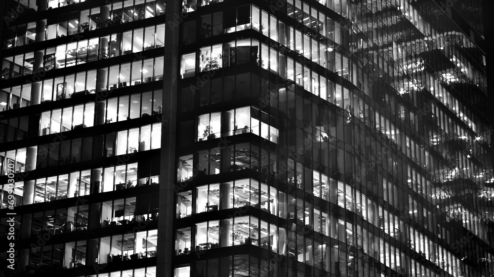 Obraz premium Pattern of office buildings windows illuminated at night. Glass architecture ,corporate building at night - business concept. Black and white.