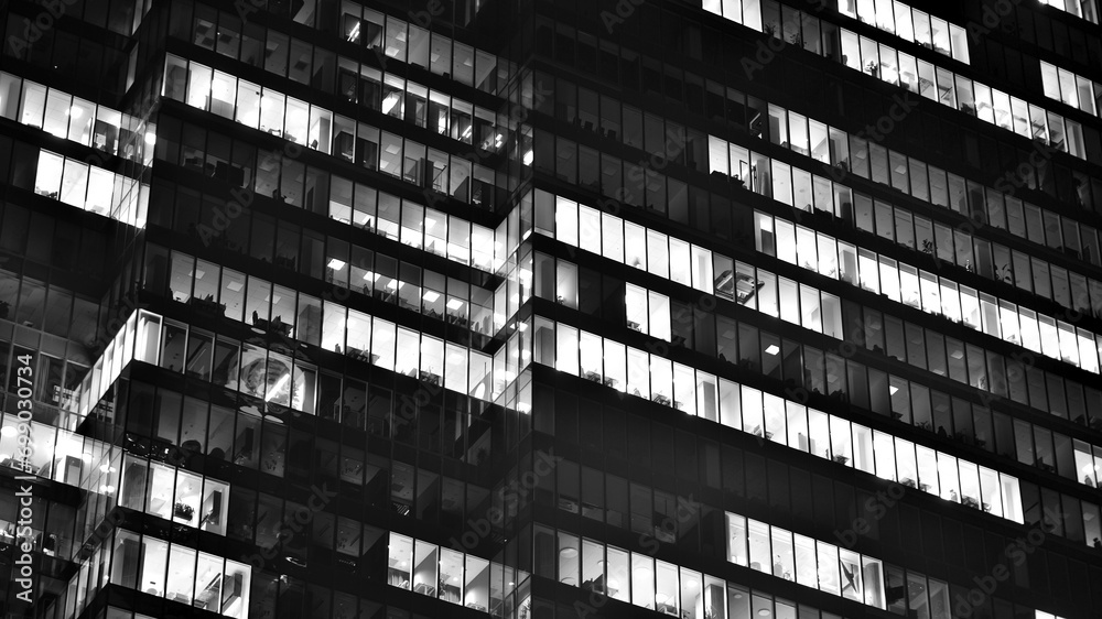 Obraz premium Pattern of office buildings windows illuminated at night. Glass architecture ,corporate building at night - business concept. Black and white.