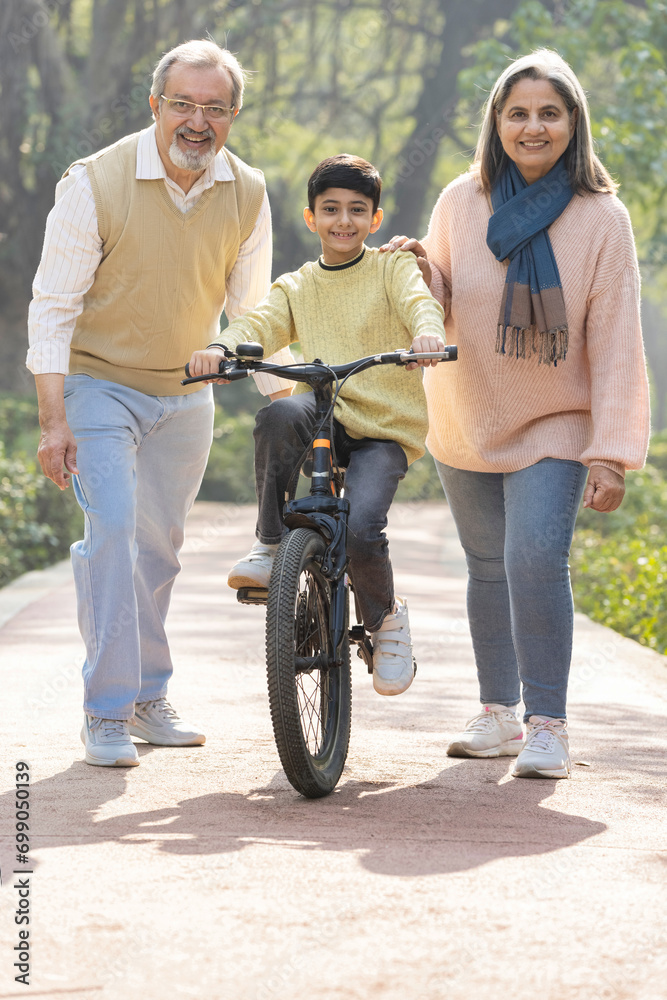Grandparents teaching cycling to grandchildren in public park Grandparents teaching cycling to grandchildren in public park