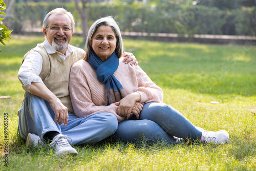Portrait of Indian senior couple embracing while standing in park. © G-images