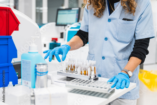 Unrecognizable healthcare worker in lab coat processes blood tests with machinery for simultaneous analysis in a clinical setting photo