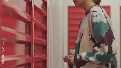 Midsection shot of woman unlocking padlock with key and opening door of self storage unitMidsection shot of woman unlocking padlock with key and opening door of self storage unit