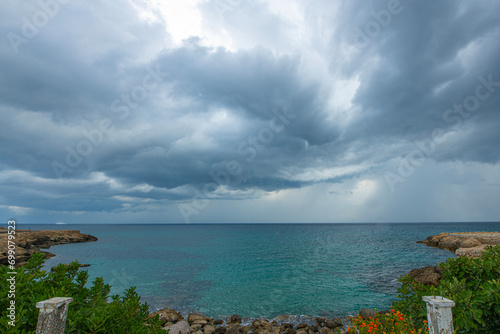 Looking at the sea from the coastal green area. Looking at the sea from the rocks on a cloudy day. Sea view from red cliffs.Cyprus coast.