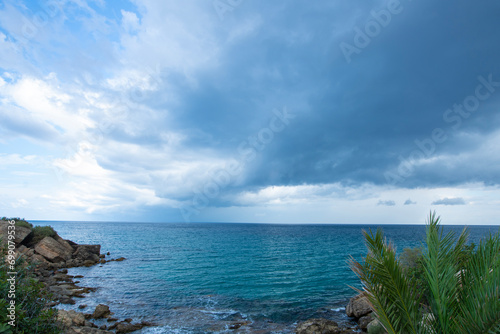 Looking at the sea from the coastal green area. Looking at the sea from the rocks on a cloudy day. Sea view from red cliffs.Cyprus coast.