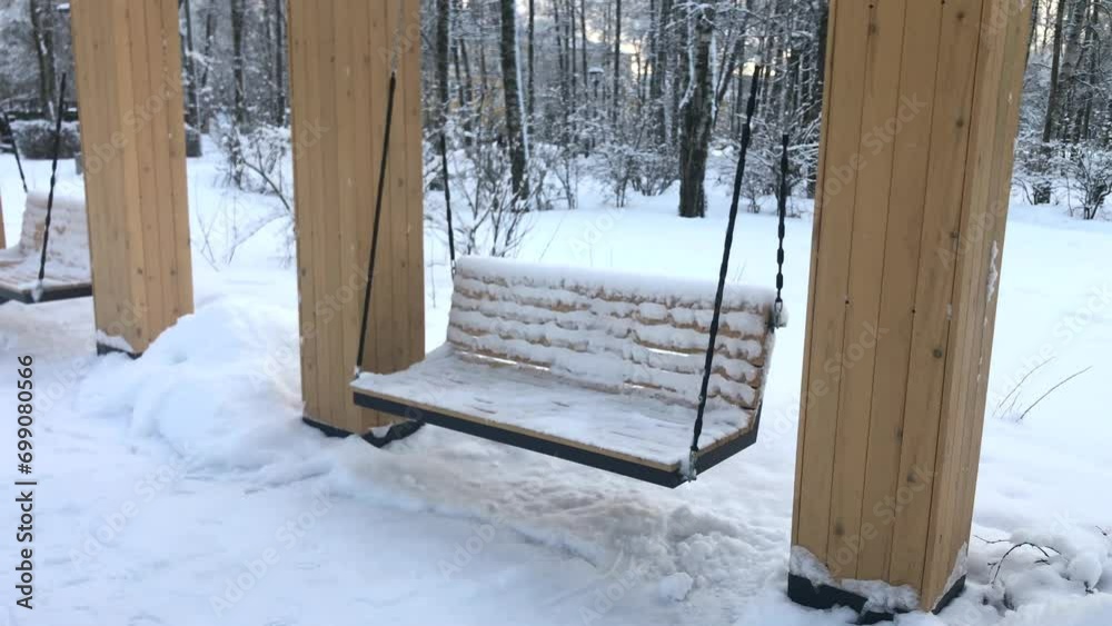 An empty bench is swinging in a winter snow park. The concept of continuing time without me, abandonment and loneliness. An empty bench is swinging in a winter snow park. The concept of continuing time without me, abandonment and loneliness.