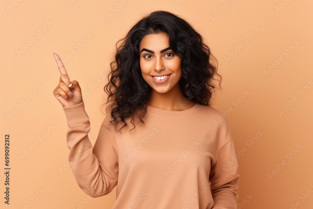 young indian woman pointing on beige color background young indian woman pointing on beige color background