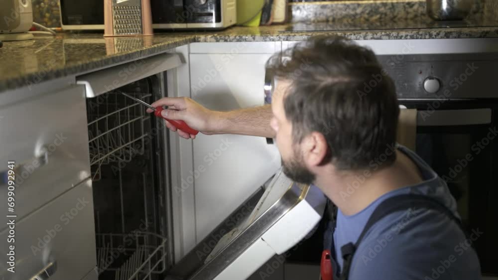 man a repairman from the service repairs the dishwasher at home man a repairman from the service repairs the dishwasher at home