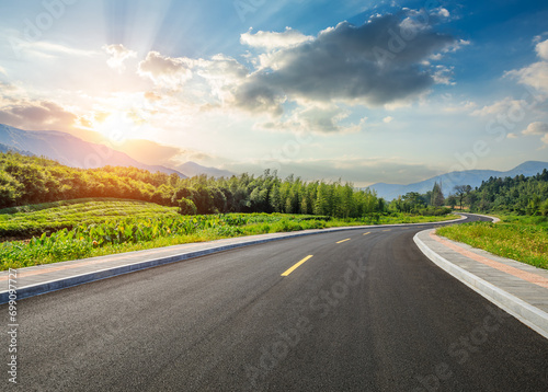 Country road and green forest with mountain nature landscape at sunset photo