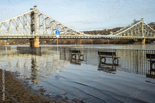 A full river that has burst its banks, with the Blue Wonder in the background. Flood in Dresden. Overflowed river bank and cycle path. Flood warning level 3