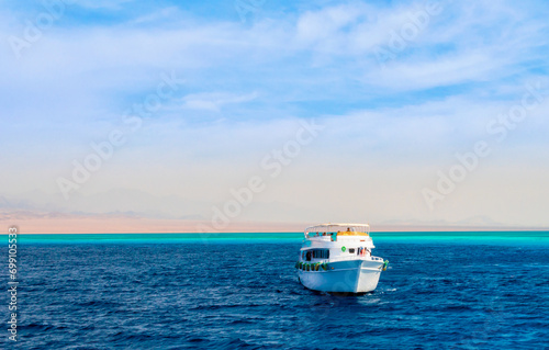 landscape tourist boat in the Red Sea on the background of a rocky shore and blue sky and clouds in Egypt in Sharm El Sheikh