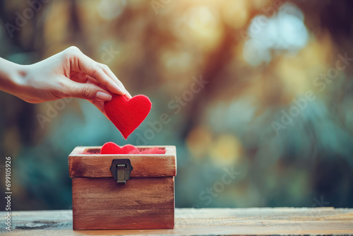 Hand Puts Red Heart Into Donation Box photo