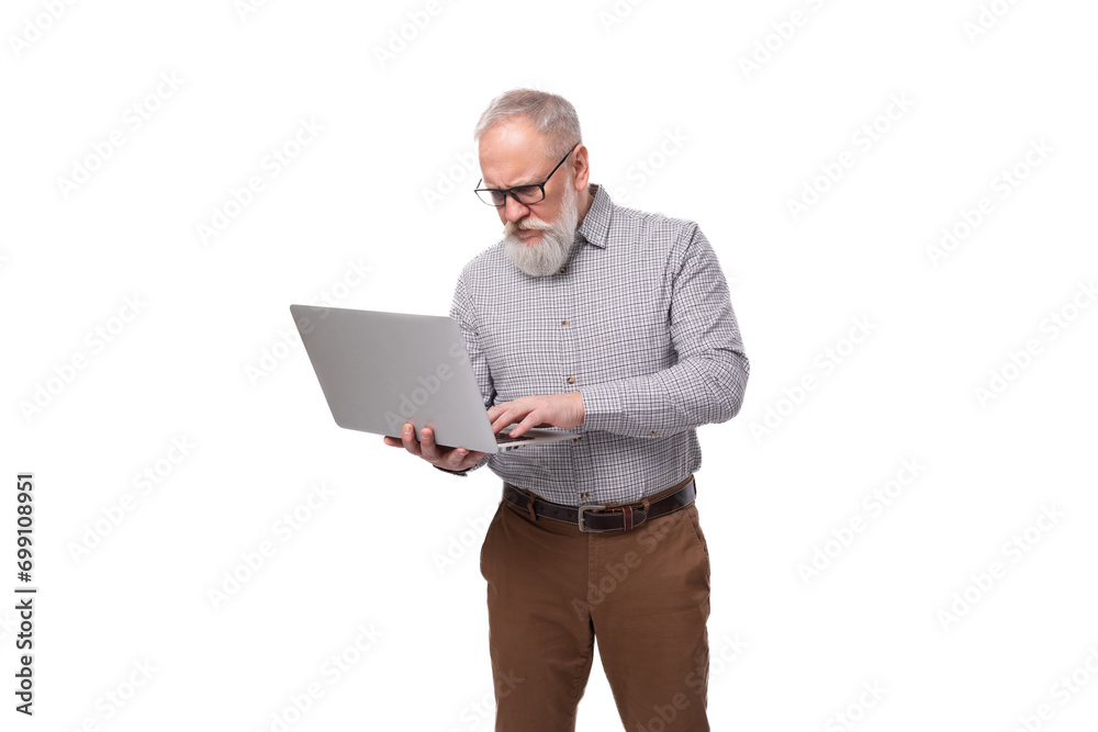successful gray-haired mature businessman with a beard and mustache in a shirt and trousers holds a laptop