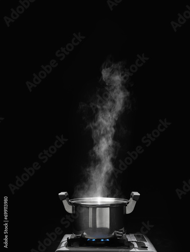 steam over cooking pot in kitchen on dark background.