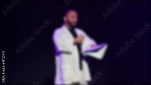 A poet at a creative evening reads poetry from the stage, blurry, no focus.