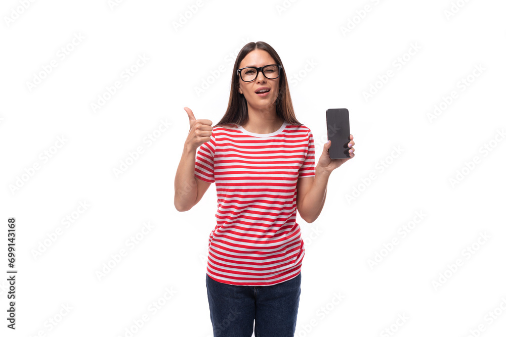 successful pretty 35 year old european lady in eyeglasses and a red striped t-shirt shows a mobile phone screen and a gesture of approval successful pretty 35 year old european lady in eyeglasses and a red striped t-shirt shows a mobile phone screen and a gesture of approval