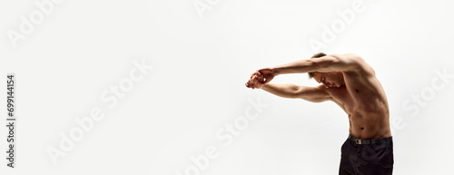 Muscular young man with relief fit shirtless body standing with round back, stanching isolated over white studio background. Concept of body care, fitness, sport. Banner. Empty space to insert text photo