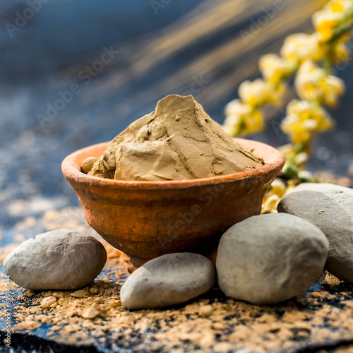 Fuller'S Earth Clay OR Multani mitti in a bowl along with raw stones and mortar photo