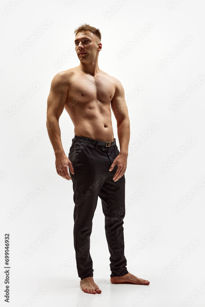 Full-length image of handsome young man with muscular relief body standing shirtless in pants isolated over white studio background. Concept of male beauty, body care, fitness, sport, health Full-length image of handsome young man with muscular relief body standing shirtless in pants isolated over white studio background. Concept of male beauty, body care, fitness, sport, health