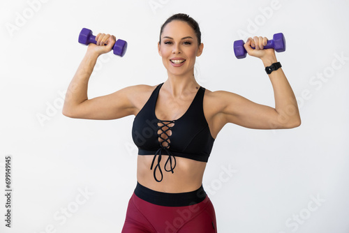 Young pretty woman working out in the gym with dumbbells.