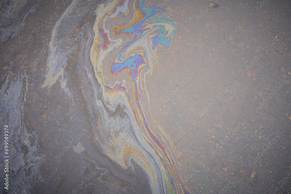 Obraz premium Close-up of an iridescent oil or gasoline spill on a wet asphalt, viewed from above.