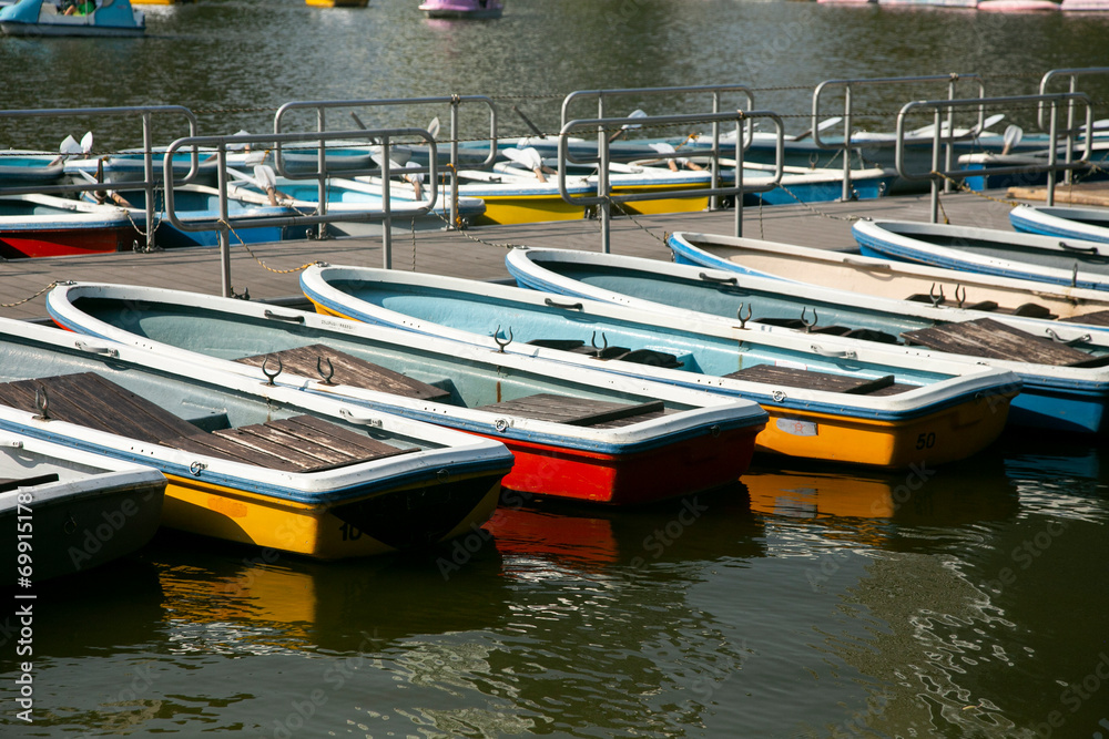 Artificial lake with boats and buildings in the background in Ueno Park in Tokyo, Japan.