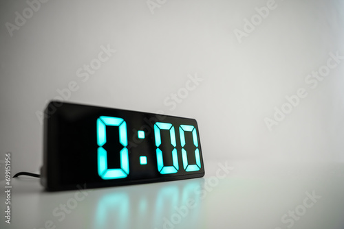 Close up of digital alarm clock at midnight time. Green numbers zero on a black screen. The start of a new day