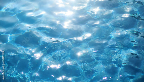 Blue water surface with ripples and sun reflections. Abstract background.