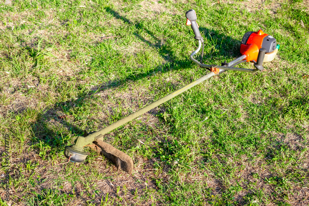 The lawnmower lies on the grass after work. Cutting grass at a summer cottage The lawnmower lies on the grass after work. Cutting grass at a summer cottage