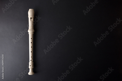 Background with overview of white plastic recorder on black background photo