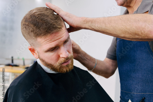 Young redhead man shaving his beard in the barbershop