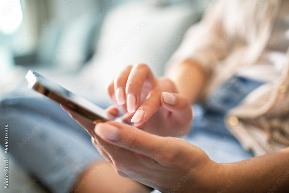 Close up woman sitting on couch using smartphone at home Close up woman sitting on couch using smartphone at home