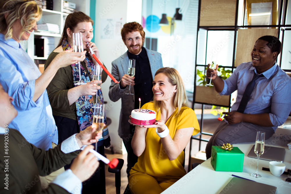 Smiling young woman celebrating birthday in office Smiling young woman celebrating birthday in office