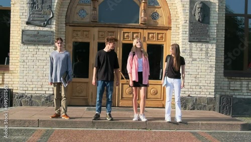 Students look at each other against front door of university. Gaining high-quality knowledge in higher education institution photo