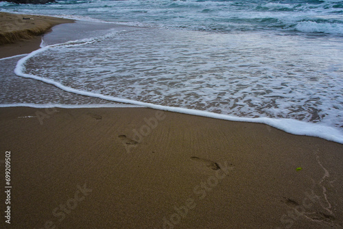 footprints in the sand and the waves washing them away symbolism of the ever-changing world of the perishability of people and the eternity of nature