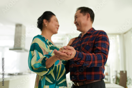 Happy aged Vietnamese couple enjoying romantic dance at home © DragonImages