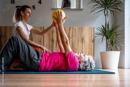 Fmale physiotherapist working on pilates and posture exercises with an elderly man photo