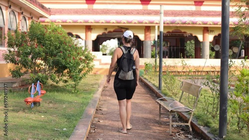 Unrecognizable female with backpack on her shoulders walks through hotel with her back to camera. 