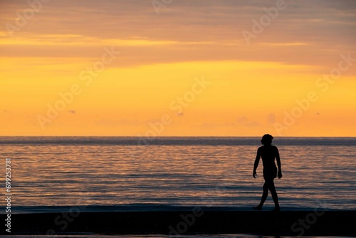Against the background of a bright sunset yellow man walking