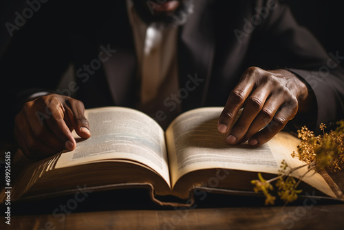 Generative AI illustration of close-up of a black anonymous person hands gently turning the pages of an open book on table with a warm light overhead