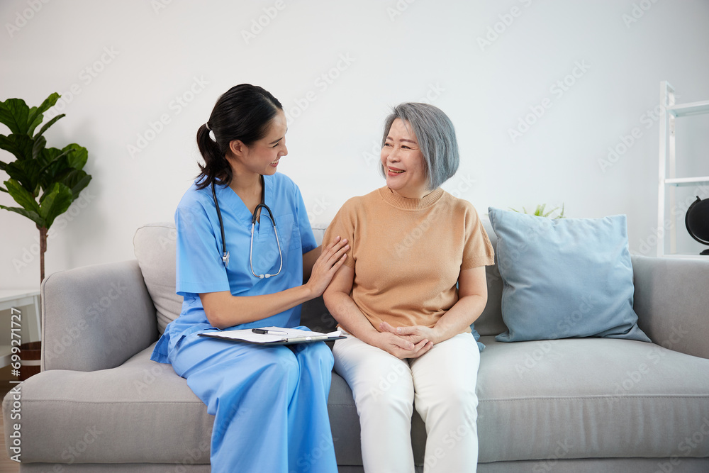 caregiver or nursing home touching arms and talking with senior woman on sofa caregiver or nursing home touching arms and talking with senior woman on sofa