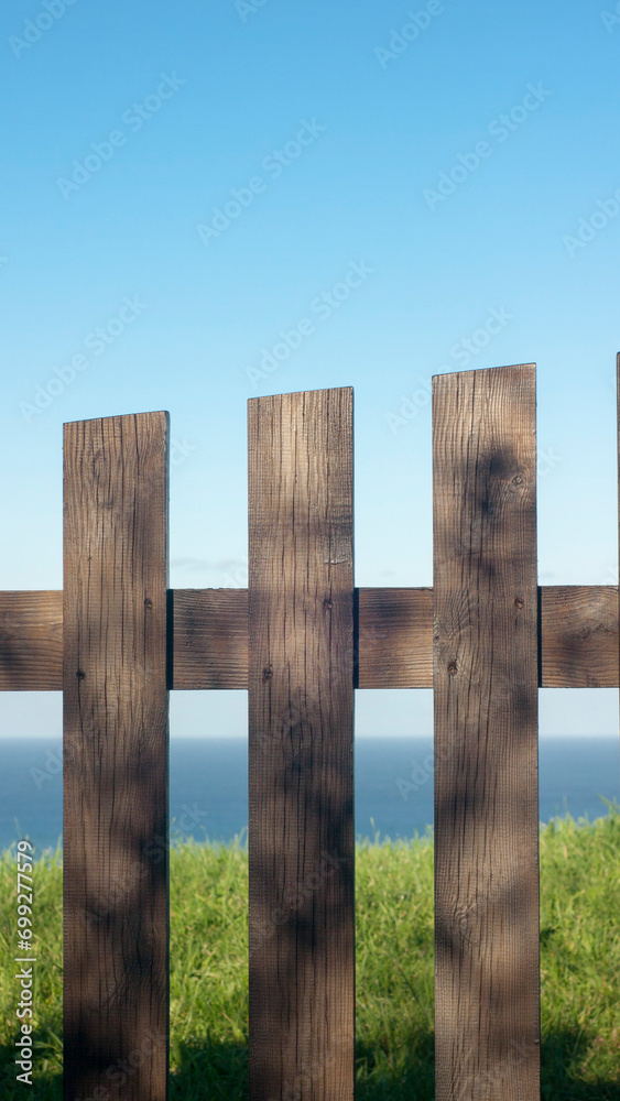 Valla de piquetes de madera en prado de hierba junto al horizonte marino