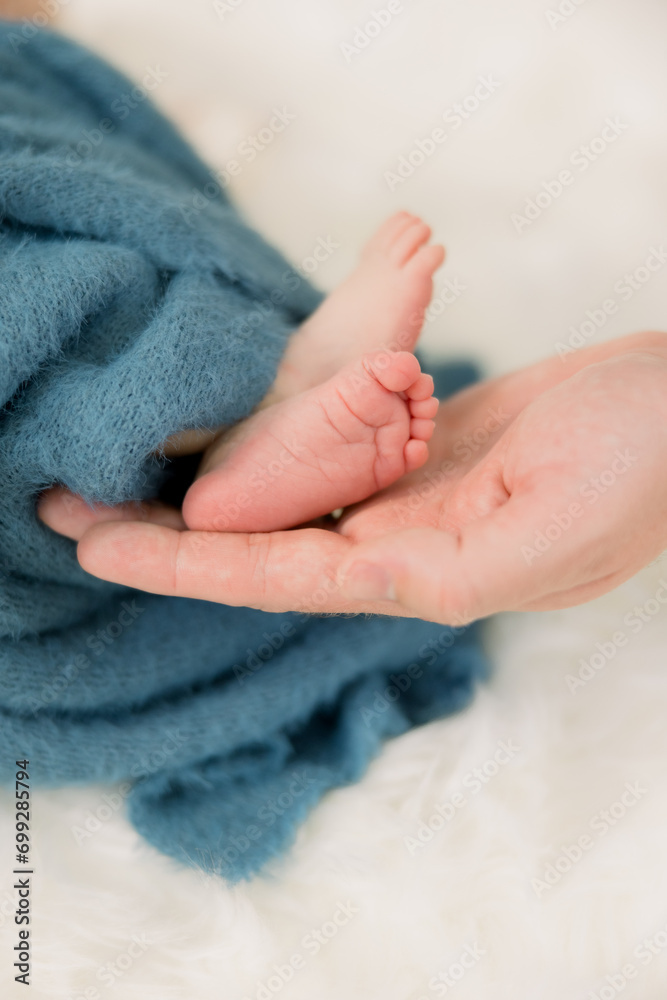 A baby is wrapped up in blue with his mother holding his tiny feet A baby is wrapped up in blue with his mother holding his tiny feet