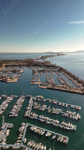 Port and Mediterranean coastline from a drone's eye view in vertical format. Tomas Maestre harbor in La manga, Murcia, Spain. Division of the Mar Menor and Mediterranean Sea. photo