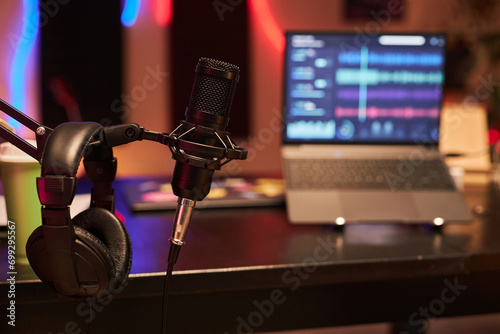 Close up shot of professional condenser microphone and headphones hanging on flexible mic stand in studio