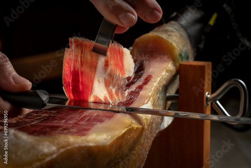 Close up of gourmet cutter slicing acorn fed iberian ham. Spanish delicatessen food. photo