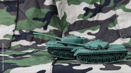 Plastic toy tank on the background of military camouflage. The concept of Russia's war against Ukraine. photo